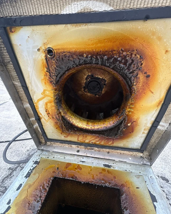 Grease buildup around a commercial kitchen exhaust fan housing before cleaning